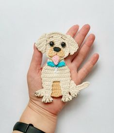 a hand holding a small crocheted dog ornament in it's palm