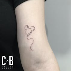 a woman's arm with a small tattoo of a mouse on the left side of her arm