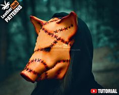 an orange leather mask with crosses on it's face is shown in front of a forest