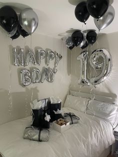 balloons and gifts on a bed in a room with the words happy birthday hanging from the ceiling