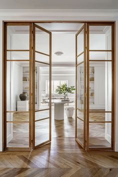 an open door leading into a living room with wooden floors and white walls in the background