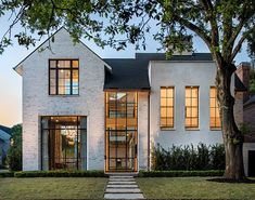 a white brick house with large windows and steps leading up to the front door is shown