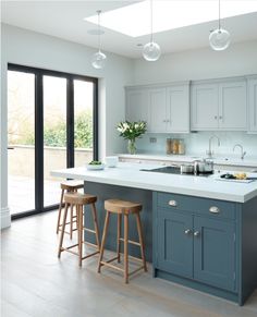 a kitchen with two stools next to an island and sliding glass doors leading outside