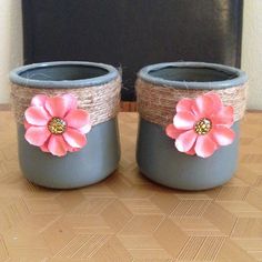 two gray pots with pink flowers are sitting on a table