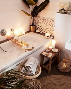 a white bath tub sitting next to a wooden table with candles on top of it