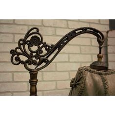 an ornate iron bed headboard against a brick wall with a lamp on the end