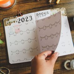 a person is holding a book in their hand next to a calendar and other items