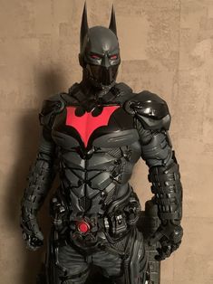 a man dressed as batman standing next to a wall