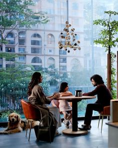 three people sitting at a table with a dog