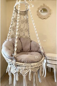 a hanging chair in the corner of a room with a mirror on the wall behind it