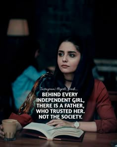 a woman sitting at a table with an open book in front of her and the quote behind her