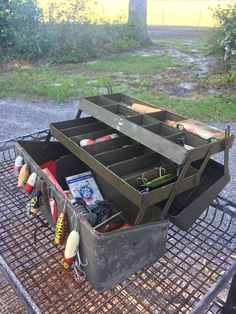 an open tool box sitting on top of a metal grate next to a field