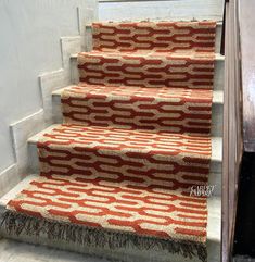 an orange and white carpeted stair runner on a set of stairs in front of a door