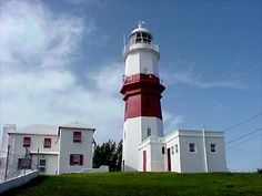 a red and white light house sitting on top of a lush green field