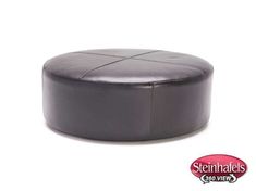 a black leather ottoman sitting on top of a white floor next to a red sign