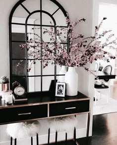 a black and gold console table with flowers in vases on top, mirror over it