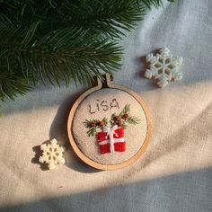 a cross stitch ornament hanging from a christmas tree next to snowflakes