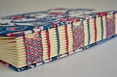 a close up of an open book on a white surface with blue, red and pink designs