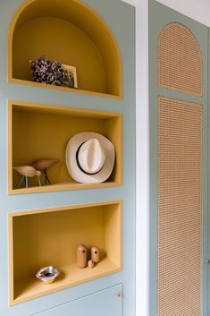 a hat is sitting on top of some shelves in a room that has blue walls and yellow trim