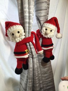 two crocheted santa clause dolls hanging from the curtain in front of a window