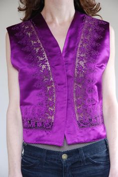 Gianni Versace 1990's silk satin fancy cut out lace vest. Super cool paired with your favorite high waisted jeans in a boho rock star look or maybe more party Euro trash with a black leather pencil skirt. Super shiny luminous royal purple color!Beautiful embroidery with elaborate lace cutouts bordering the hem. One button at front that can be closed or left open if you wish. Fully lined. Label Gianni Versace, Made in Italy. 100% silk, dry clean only. Size 42. Good vintage condition - to note is Fitted Vintage V-neck Vest, Formal Silk Vest For Spring, Fitted Silk Summer Vest, Vintage Party Vest For Spring, Vintage Spring Party Vest, Spring Party Vintage Vest, Vintage Fitted Party Vest, Fitted V-neck Vintage Vest, Versace 1990's