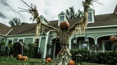 an outdoor halloween scene with pumpkins on the ground and trees in front of a house