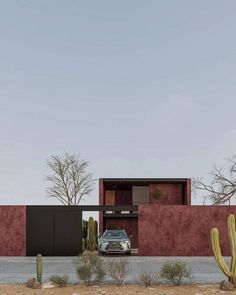 a car is parked in front of a red building with cactus and cacti