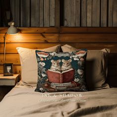 a bed with a pillow that has two mice reading a book on it and a lamp next to it