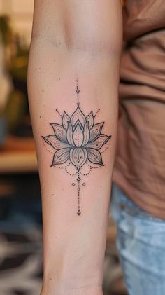 a woman's arm with a tattoo on it that has a lotus flower in the center