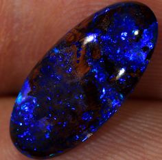 a large blue stone sitting on top of a persons finger