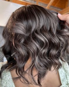 the back of a woman's head with gray hair and wavy, dark brown hair