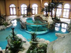 an indoor swimming pool surrounded by rocks and plants