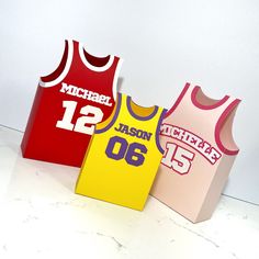 three basketball jersey shaped boxes sitting on top of a white counter next to each other