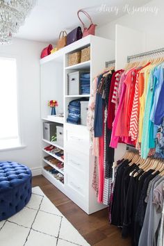 an organized closet with clothes, shoes and handbags on hangers next to a blue tufted ottoman