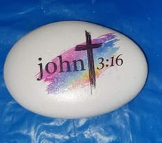 a painted rock with a cross and the word john 3 16 written on it in rainbow ink