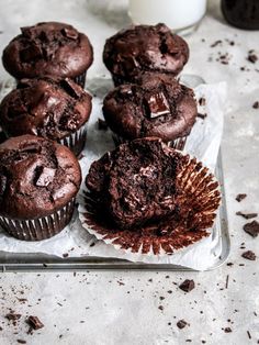 several chocolate muffins on a tray next to a glass of milk