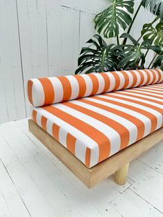 an orange and white striped couch sitting on top of a wooden table next to a potted plant