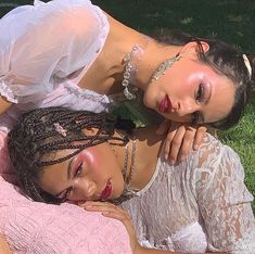 two beautiful women laying on top of each other next to each other in the grass