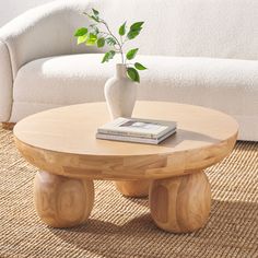 a coffee table with a book on it and a vase sitting on top of it