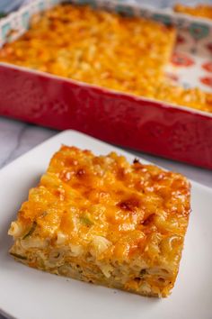 a piece of casserole sitting on top of a white plate next to a red dish