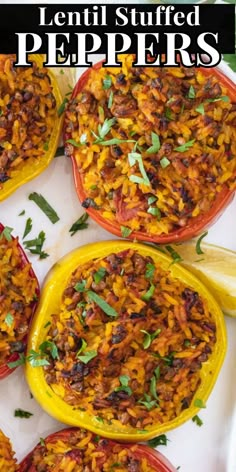 several stuffed peppers on a white platter with lemon wedges and parsley garnish