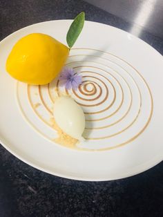 a white plate topped with a lemon and an egg on top of a black table