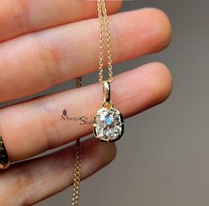 a person holding a gold necklace with a diamond in it's center and an inscription on the back