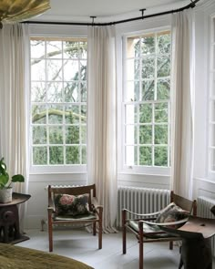 a room with two chairs and three windows