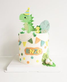 a birthday cake that is decorated like a dinosaur and has decorations on the top tier