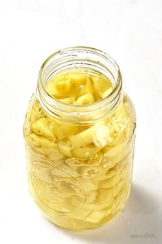 a jar filled with sliced bananas sitting on top of a white table next to a banana peel