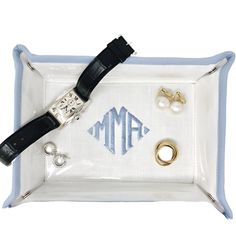 a white tray with two rings and some other items on it, including a watch