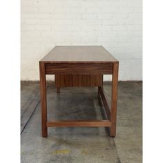 a small wooden table sitting in front of a white brick wall on concrete flooring