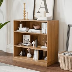 a wooden shelf with books and pictures on it next to a potted plant in a living room