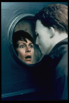 a woman looking at herself in the mirror with her mouth open and another person standing next to her